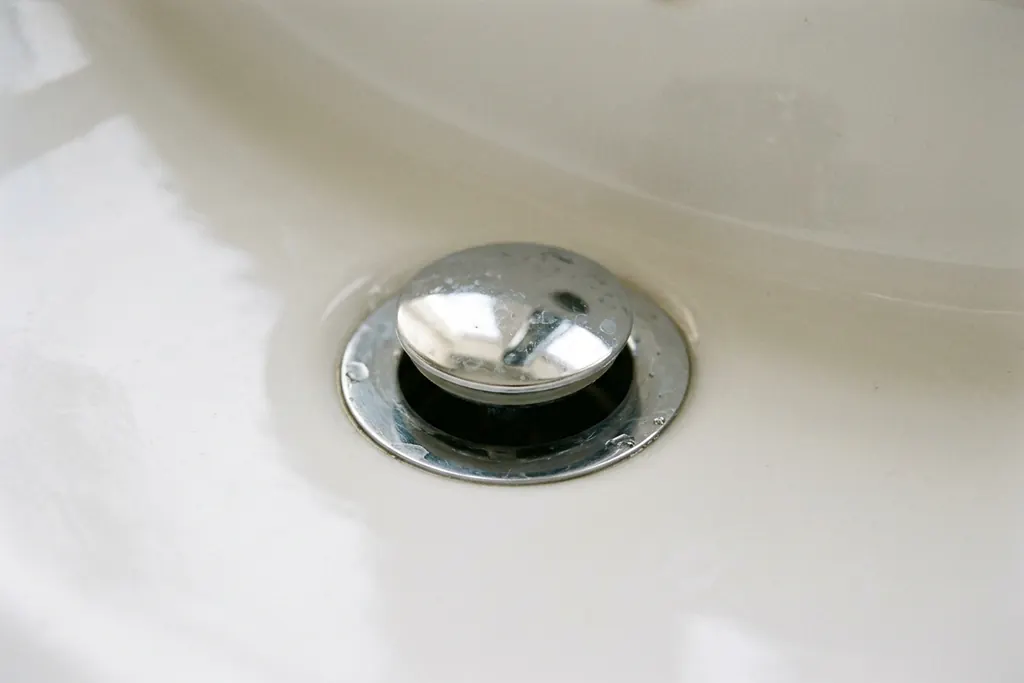 Close-up of a bathroom basin plughole with a chrome pop-up waste